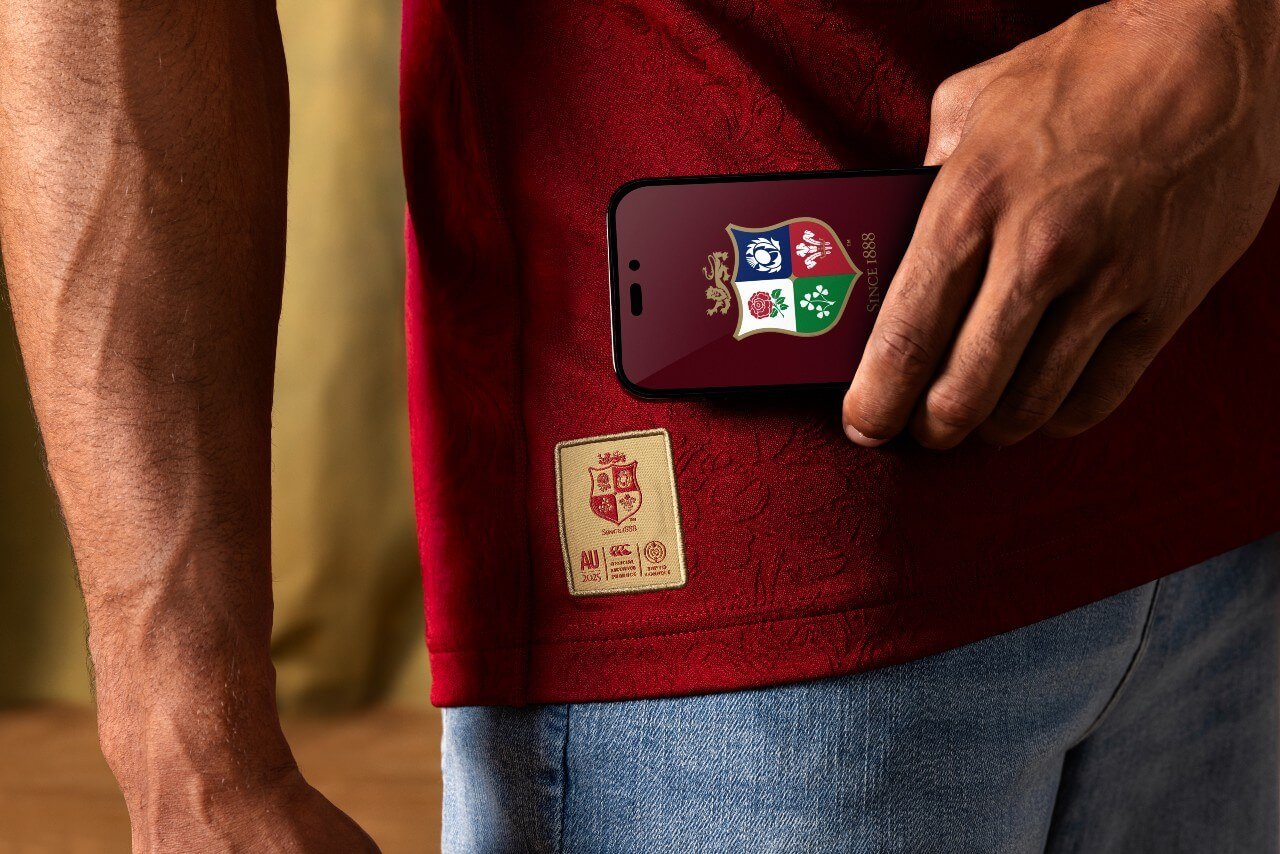 Close up of the jersey smart tag with a phone screen being held next to it displaying the The British & Irish Lions badge