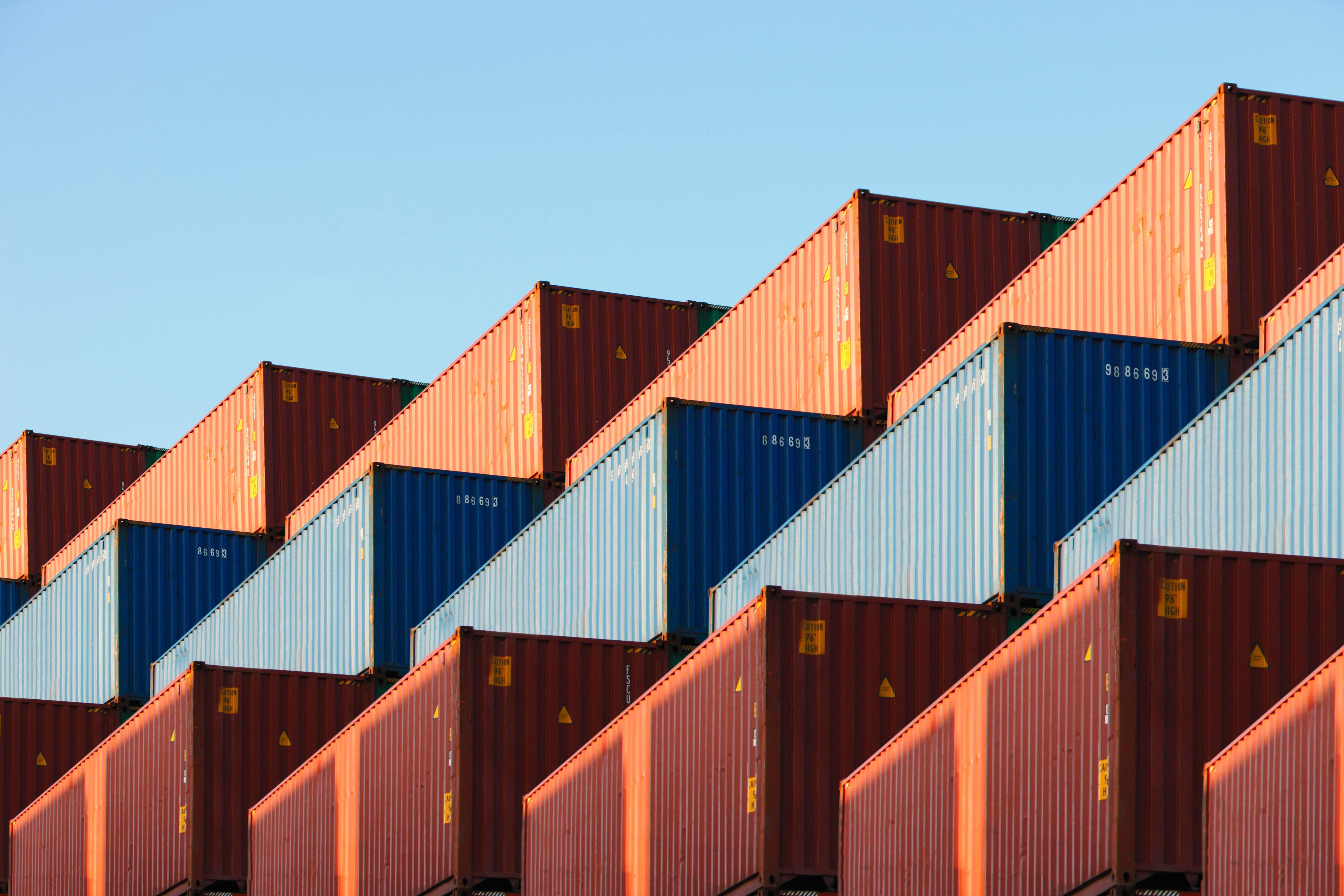 Colourful shipping containers stacked against the sunlight in a chevron-like pattern